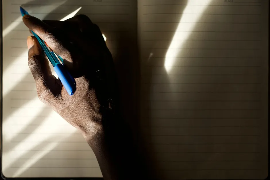A person writing in a journal by hand in soft morning light